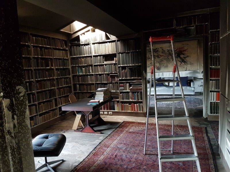 Domowa biblioteka po pożarze przed pracami BELFOR – ściany, sufit i regały z książkami pokryte sadzą